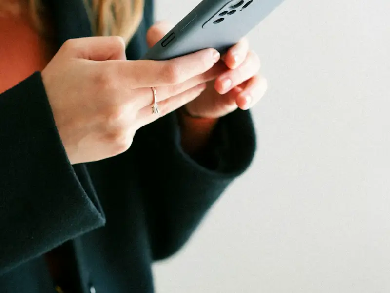 Hands typing a message on a phone.